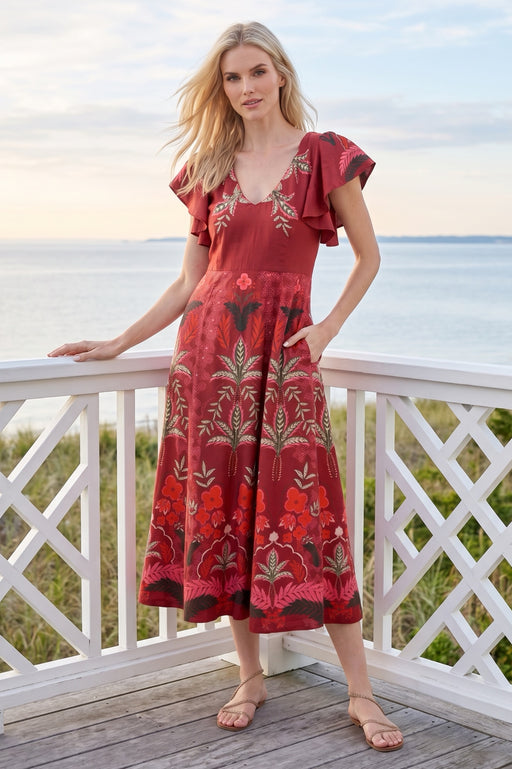 Woman wearing a red v-neck midi dress with floral print, side pockets, and short flutter sleeves from Johnny Was