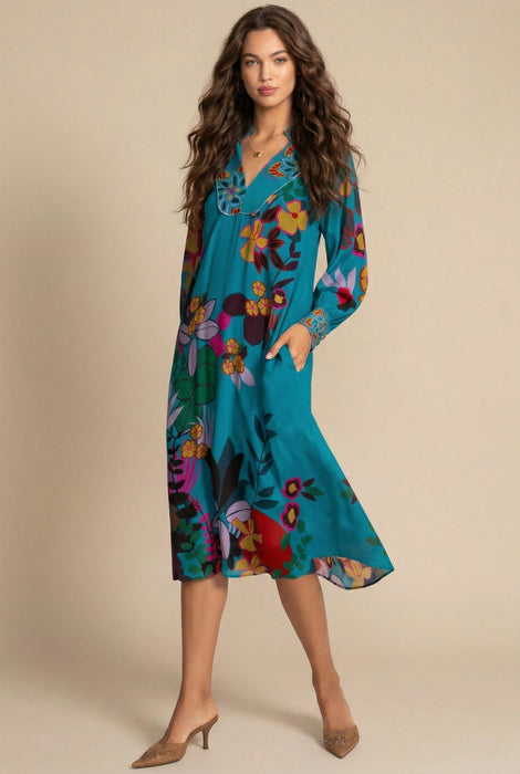 Woman wearing a vibrant turquoise floral printed midi dress with v-neck and side pockets from Johnny Was