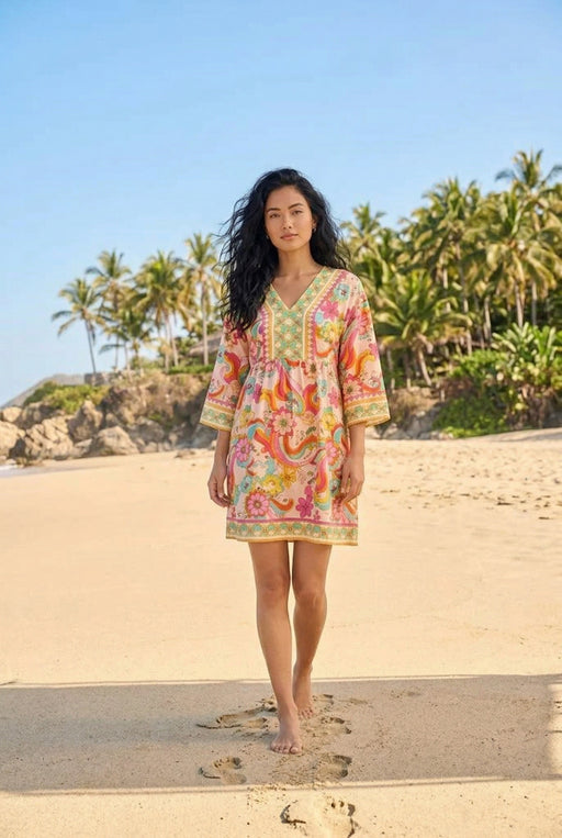 Woman wearing Johnny Was Jade Prismatic Dream Barbara Mini Dress Petite featuring a vibrant floral print, V-neckline, and flowy sleeves, styled for effortless beach-ready boho style.