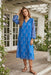 Woman wearing blue semi-sheer midi dress with floral print and long sleeves from Johnny Was