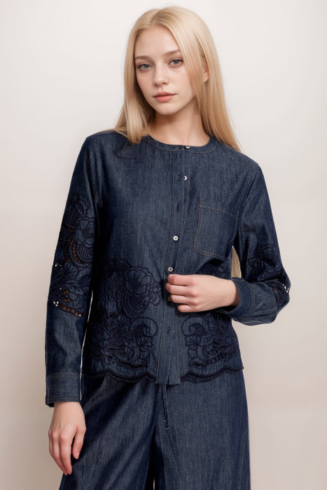 Woman wearing a dark wash denim blouse with embroidery and button front