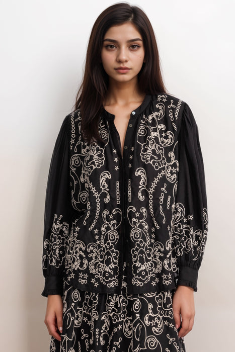 Woman wearing a black embroidered top with button front and long sleeves