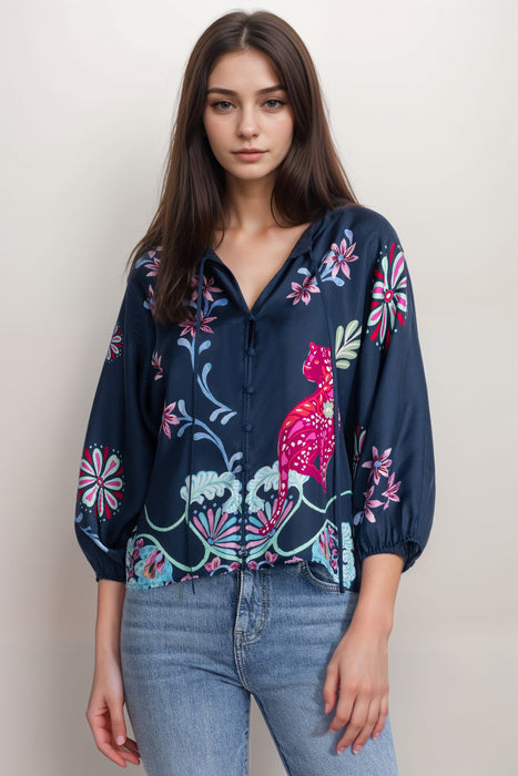 Woman wearing a navy top with 3/4 puff sleeves and floral print from Johnny Was