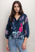 Woman wearing a navy top with 3/4 puff sleeves and floral print from Johnny Was