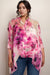 Woman wearing a pink floral sheer silk top with 3/4 sleeves and button front closure