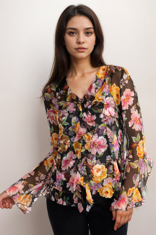 Woman wearing a colorful v-neck silk blouse with floral print and ruffles from Johnny Was