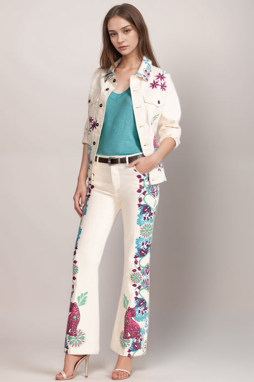 Woman wearing a cream-colored flared jean with printed outseams from Johnny Was