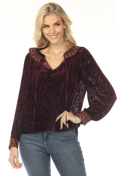Woman wearing a burgundy blouse with burnout velvet paisley patterns and sequin embroidered collar and cuffs from Johnny Was