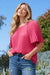 Woman wearing a bright pink pleated blouse with short sleeves from Johnny Was