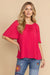 Woman wearing a bright pink pleated blouse with short sleeves from Johnny Was