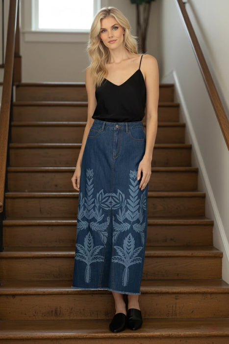 Woman wearing a blue maxi denim skirt with white leaf pattern and frayed hem from Johnny Was