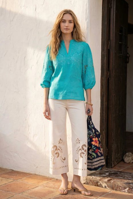 Woman wearing a turquoise embroidered blouse with split v-neck and puff sleeves from Johnny Was