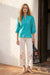 Woman wearing a turquoise embroidered blouse with split v-neck and puff sleeves from Johnny Was