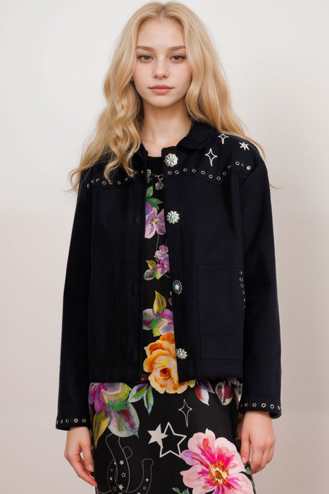 Woman wearing a black jacket with star embroideries and grommets