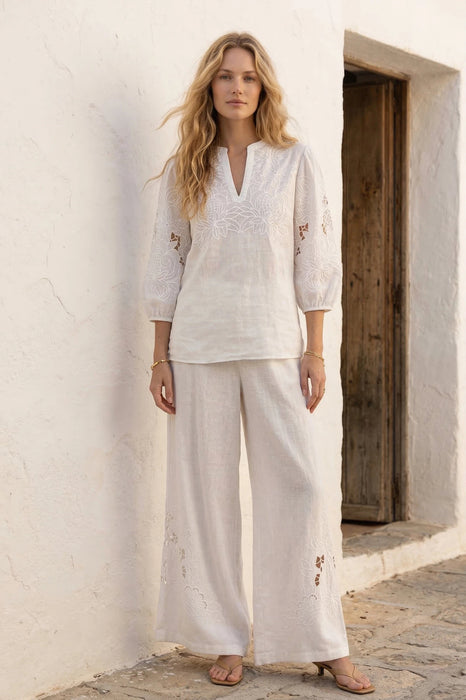 Woman wearing a white embroidered blouse with split v-neck and puff sleeves from Johnny Was