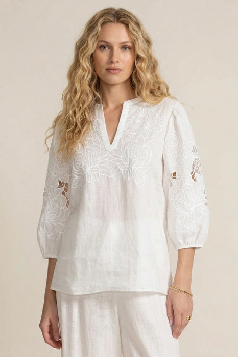 Woman wearing a white embroidered blouse with split v-neck and puff sleeves from Johnny Was