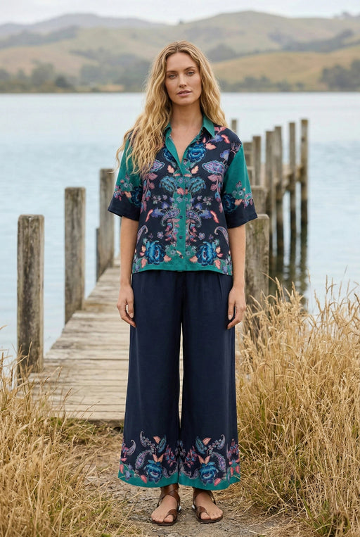 Woman wearing a navy blue cropped wide leg pants with floral print at the hem and pull on elastic waistband from Johnny Was
