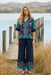 Woman wearing a navy blue cropped wide leg pants with floral print at the hem and pull on elastic waistband from Johnny Was