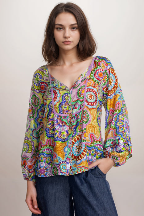 Woman wearing a colorful patterned silk shirt with button front and puff sleeves