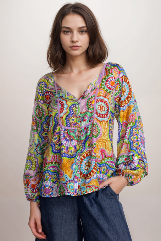 Woman wearing a colorful patterned silk shirt with button front and puff sleeves