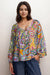 Woman wearing a colorful patterned silk shirt with button front and puff sleeves