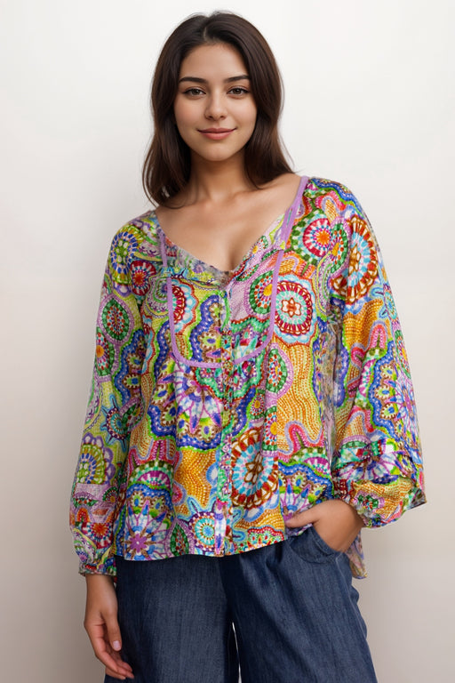 Woman wearing a colorful patterned silk shirt with button front and puff sleeves