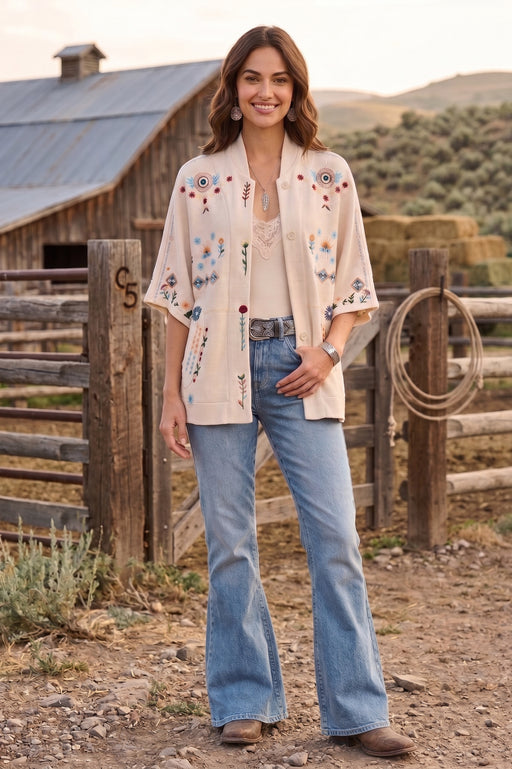 Woman wearing a beige poncho with colorful embroideries and front clasp closure from Johnny Was