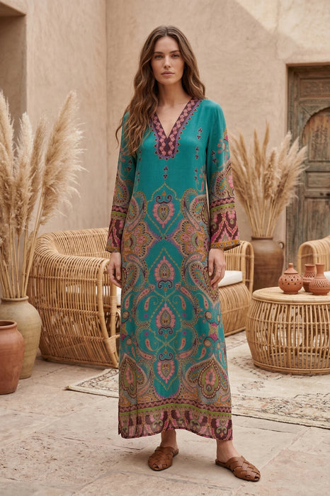 Woman wearing a blue v-neck maxi dress with paisley print and long sleeves from Johnny Was