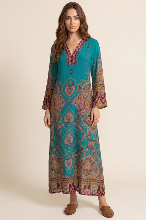 Woman wearing a blue v-neck maxi dress with paisley print and long sleeves from Johnny Was
