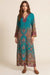 Woman wearing a blue v-neck maxi dress with paisley print and long sleeves from Johnny Was