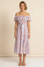 Woman wearing an off-shoulder midi dress with circle waves print and waist sash from Johnny Was