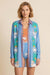 Woman wearing a blue lightweight button down shirt with colorful palm tree and lion prints from Johnny Was