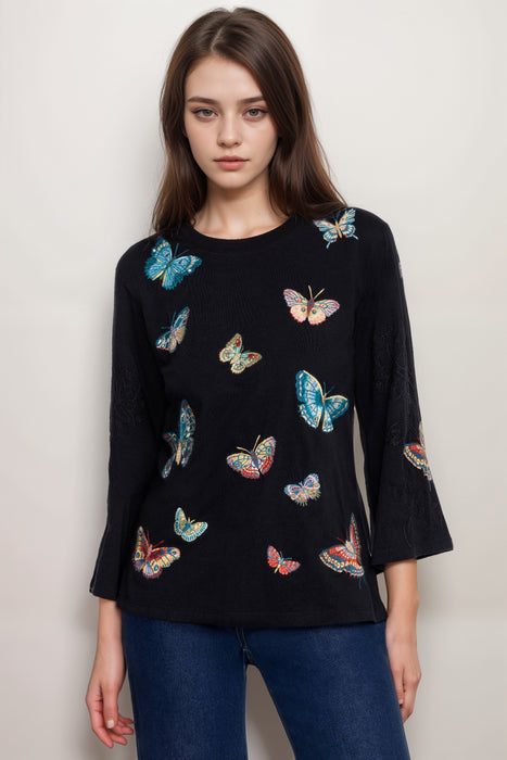 Woman wearing a black cotton top with butterfly embroideries and 3/4 kimono sleeves from Johnny Was