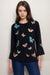 Woman wearing a black cotton top with butterfly embroideries and 3/4 kimono sleeves from Johnny Was