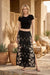 Woman wearing a black floral embroidered maxi skirt from Johnny Was