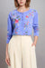 Woman wearing a blue henley top with floral embroidery and raw seam detail from Johnny Was