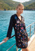 A woman wearing a black long-sleeve mini dress with colorful floral embroidery and hoodie from Johnny Was