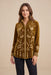 A woman modeling a long-sleeve button-up shirt made of rich olive-brown velvet with intricate cream floral embroidery, paired with black pants, against a solid beige studio background.