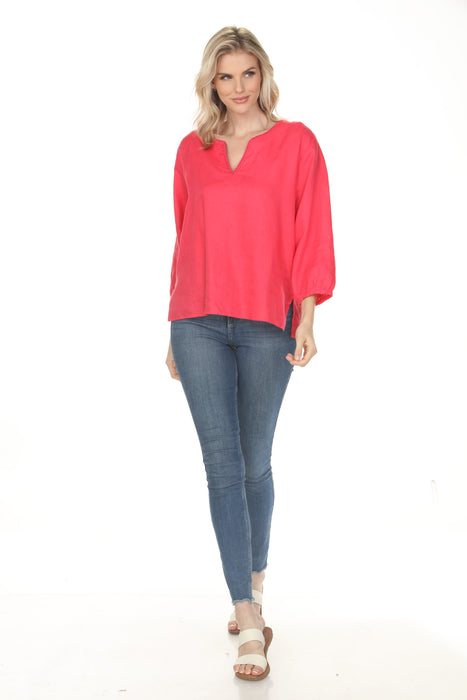 A woman wearing a bright coral pink long-sleeve top and blue skinny jeans, posed diagonally on a solid white background.