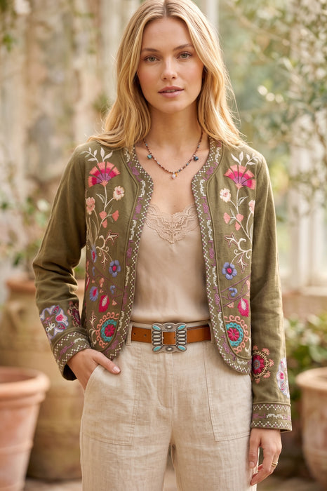 Woman wearing a green open front bolero jacket with colorful floral embroidery and long sleeves from Johnny Was