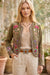 Woman wearing a green open front bolero jacket with colorful floral embroidery and long sleeves from Johnny Was