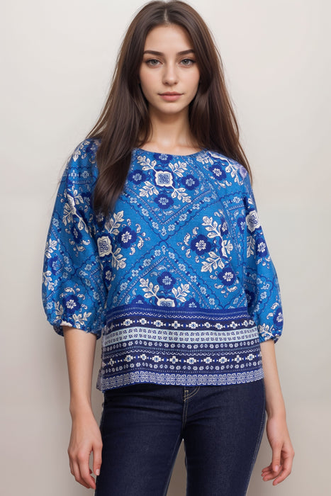 Woman wearing a blue linen blouse with tile-like pattern and fair isle hem