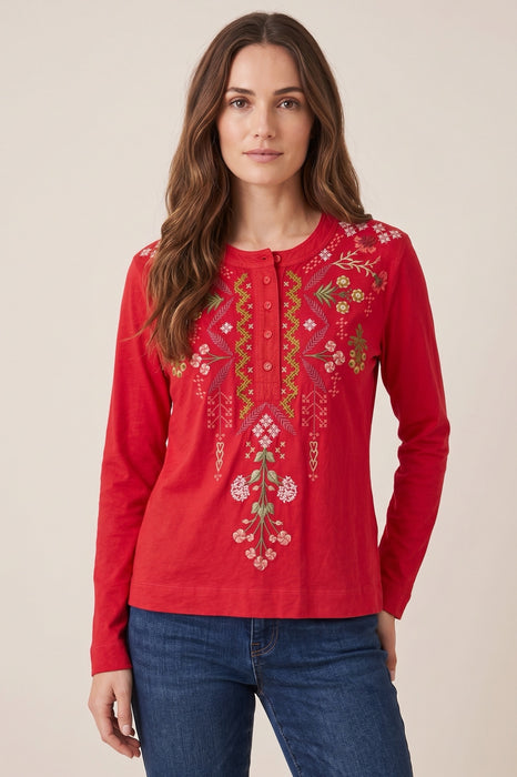 Woman wearing a red embroidered long-sleeve top with henley neckline from Johnny Was