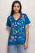 Woman wearing a blue t-shirt with colorful embroideries at the front from Johnny Was