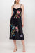 Woman wearing a black linen midi slip dress with floral embroidery and adjustable spaghetti straps from Johnny Was