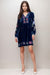 Woman wearing a navy velvet shift dress with colorful embroidery and long sleeves from Johnny Was