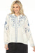Woman wearing a white linen jacket with blue floral embroideries and button front from Johnny Was