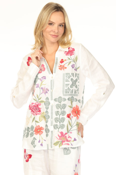 Woman wearing a white long-sleeve top with colorful floral embroidery and button front closure from Johnny Was