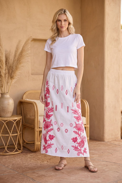 Woman wearing a white floral embroidered maxi skirt from Johnny Was
