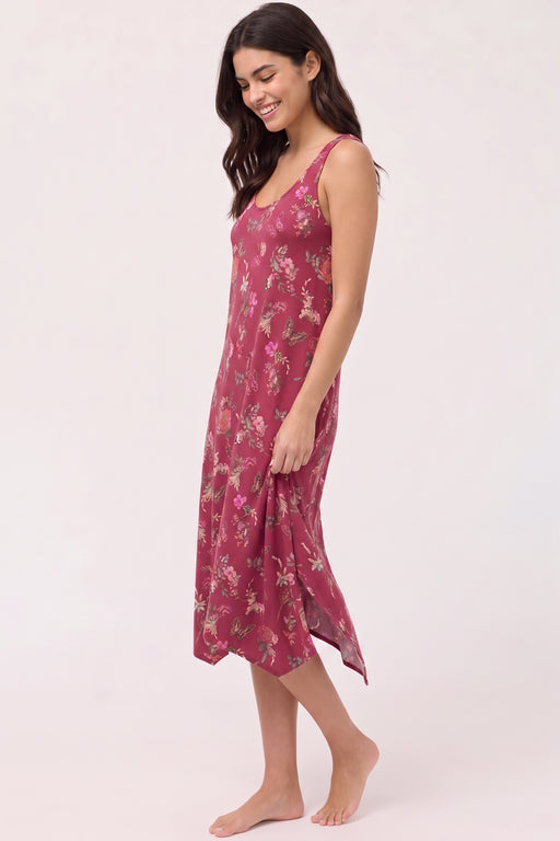 A woman modeling a sleeveless midi-length slip dress with a dusty rose floral print against a plain light background.
